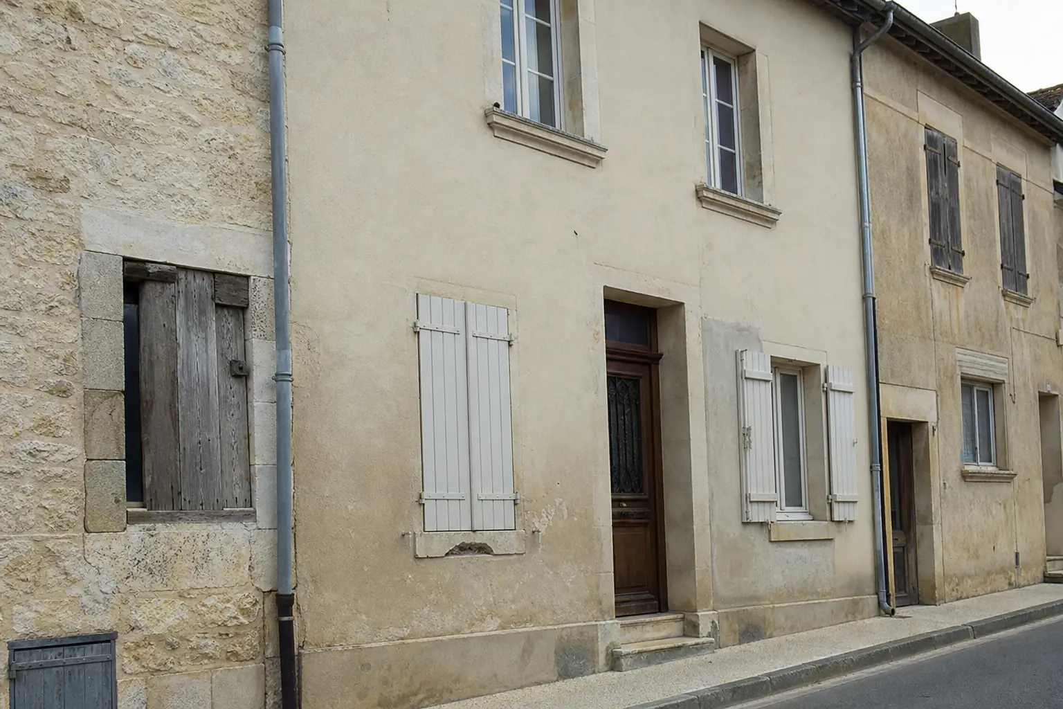 Façade de maison de bourg en pierre et enduit à la chaux, gouttière de zinc et descente d'eau pluviale