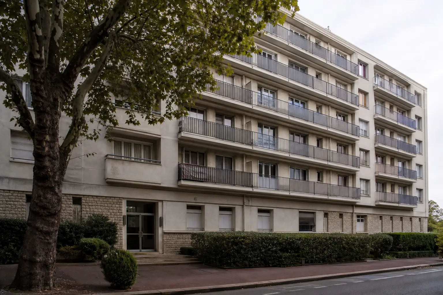 Immeuble d'habitation collectif des années 1960 vu de la rue, façade claire, balcons filants sur six étages
