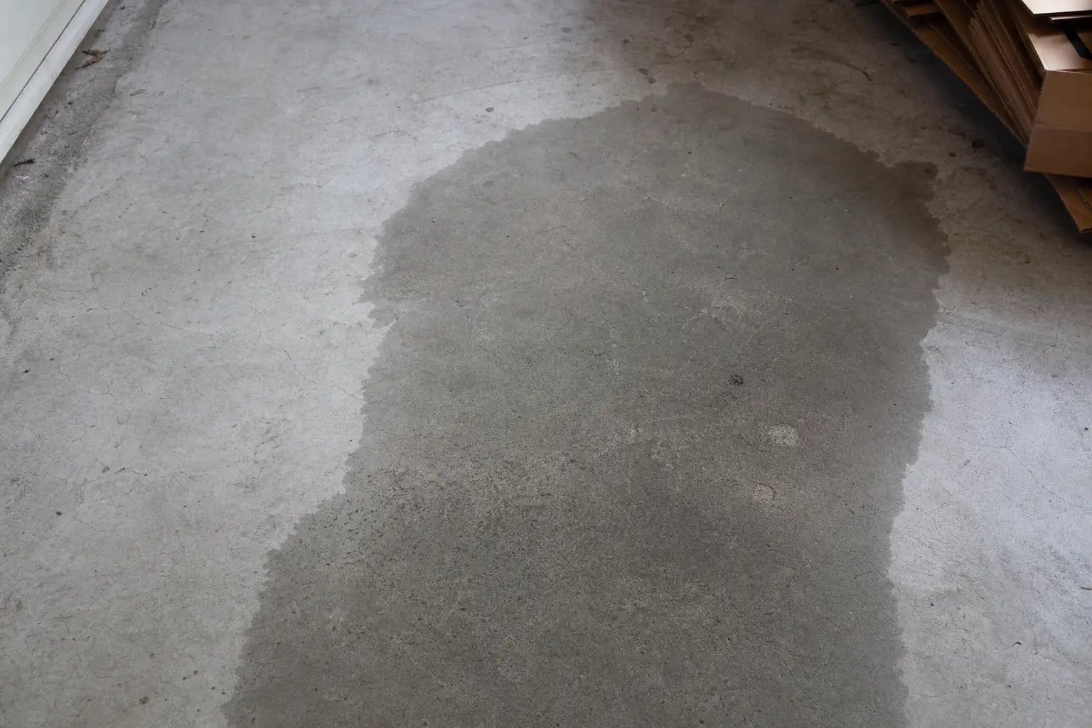 Sol de garage en béton brut portant une large zone d'humidité au contour net